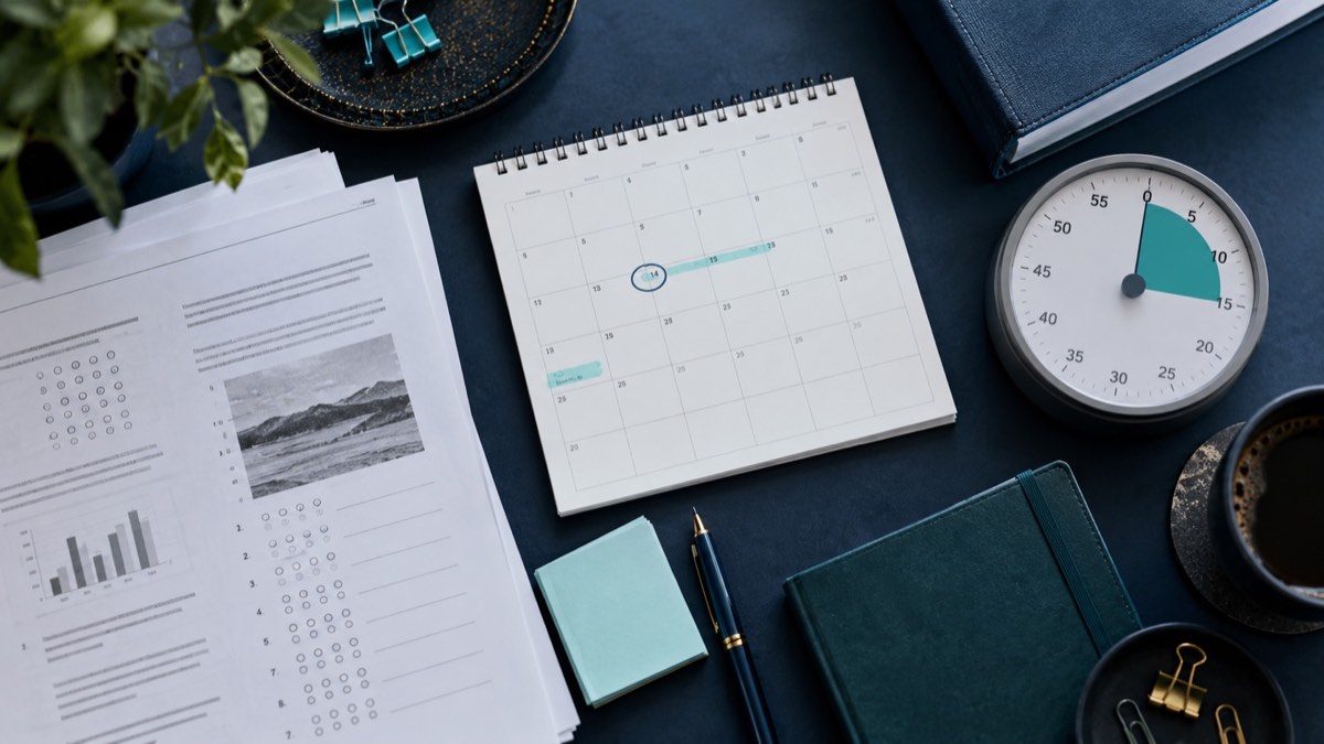 A study timetable and progress sheets beside an analog clock.